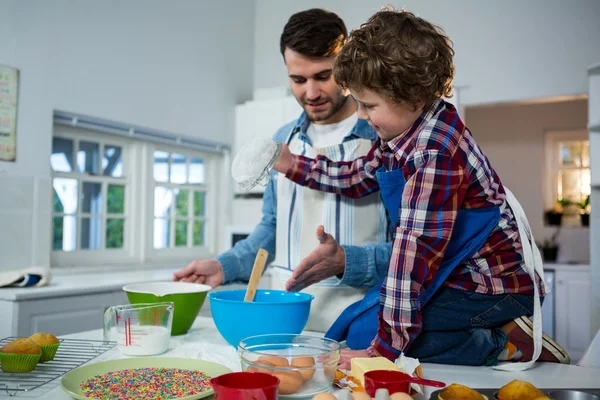 Father teaching his son how to make cupcake