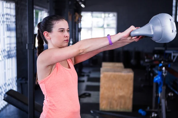 Atleta femenina sosteniendo kettlebell en gimnasio —  Fotos de Stock