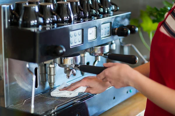 Garçonete limpando máquina de café expresso com guardanapo — Fotografia de Stock