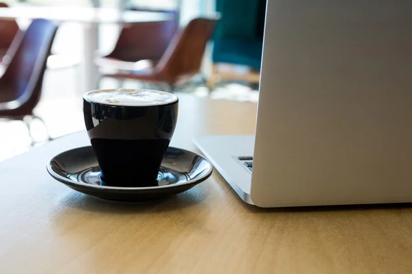 Cup of coffee and laptop on table — Stock Photo, Image