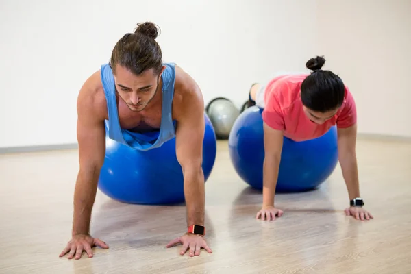 Los hombres haciendo push-up en la pelota de ejercicio —  Fotos de Stock