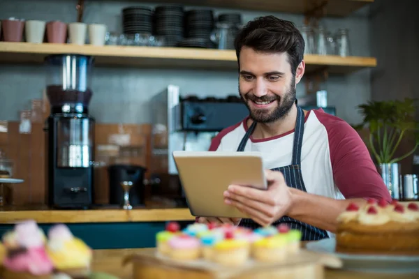 Camarero sonriente usando tableta digital en la cafetería — Foto de Stock
