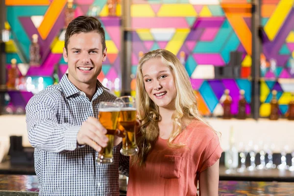Casal mostrando um copo de cerveja no bar — Fotografia de Stock