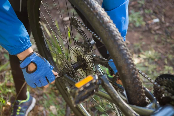 Motociclista de montanha masculino fixar sua cadeia de bicicletas — Fotografia de Stock