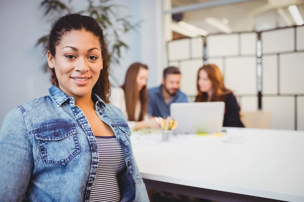 Businesswoman sitting against coworkers — Stock Photo, Image