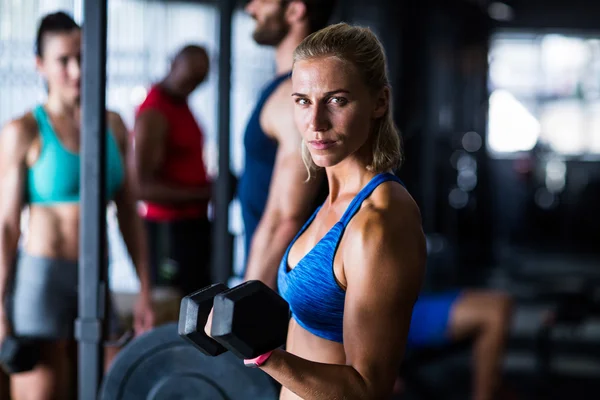 Mujer seria sosteniendo la mancuerna en el gimnasio — Foto de Stock