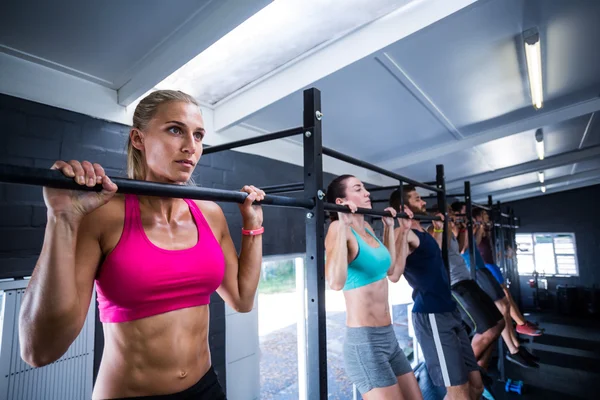 Atletas haciendo flexiones de mentón en el gimnasio — Foto de Stock