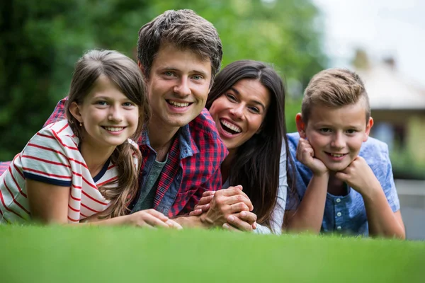 Família feliz deitada no parque — Fotografia de Stock