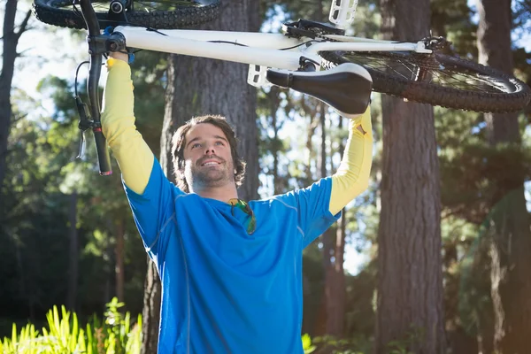 VTT homme portant un vélo dans la forêt — Photo