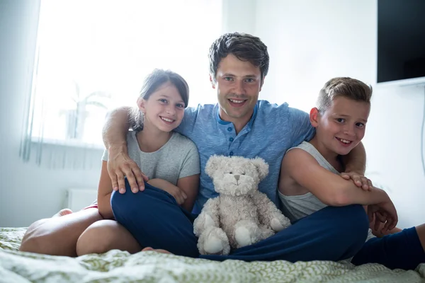 Vader en kinderen zitten in slaapkamer — Stockfoto