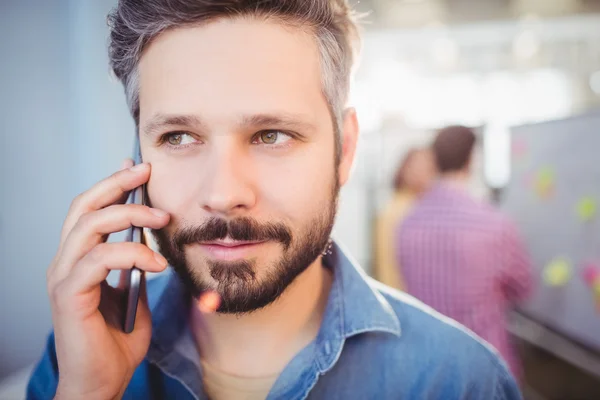Affärsman som lyssnar på mobiltelefon på kreativa kontor — Stockfoto