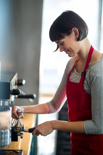 Serveerster met behulp van een stamper te drukken van gemalen koffie — Stockfoto