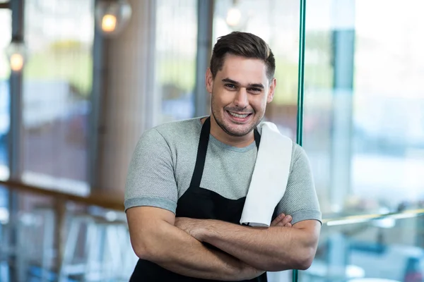 Camarero sonriente apoyado en la puerta de cristal — Foto de Stock