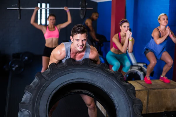 Uomo sorridente sollevare pneumatico in palestra — Foto Stock