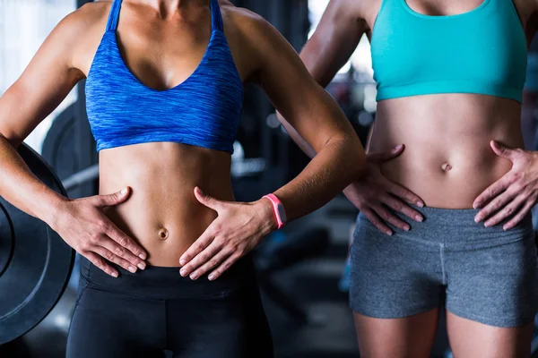 Amigos do sexo feminino tocando barriga no ginásio — Fotografia de Stock