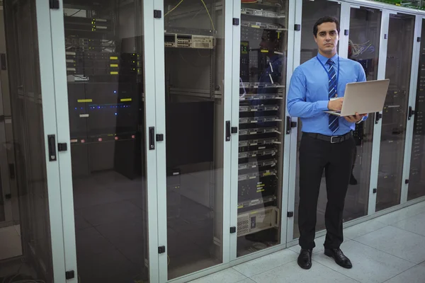 Technician using laptop while analyzing server — Stock fotografie