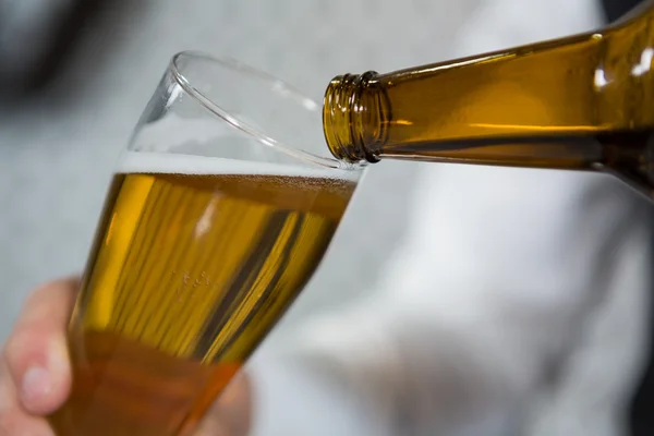 Barista versare birra in vetro — Foto Stock