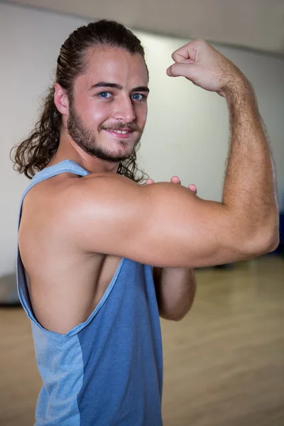 Homme souriant fléchissant son biceps — Photo