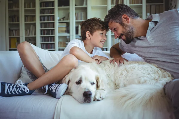 Baba ve oğul evde beslenen hayvan köpek ile kanepede oturan — Stok fotoğraf
