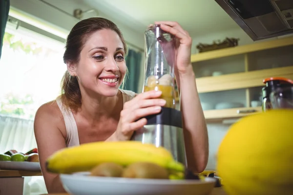 Lächelnde Frau bereitet Smoothie zu — Stockfoto