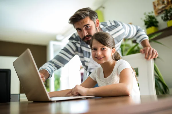 父亲和女儿在客厅里使用笔记本电脑的肖像 — 图库照片