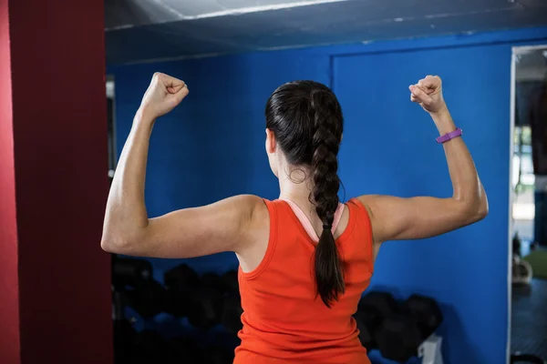 Bakifrån av kvinna flexar muskler i gymmet — Stockfoto