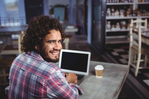 Hombre sonriendo mientras usa el ordenador portátil — Foto de Stock