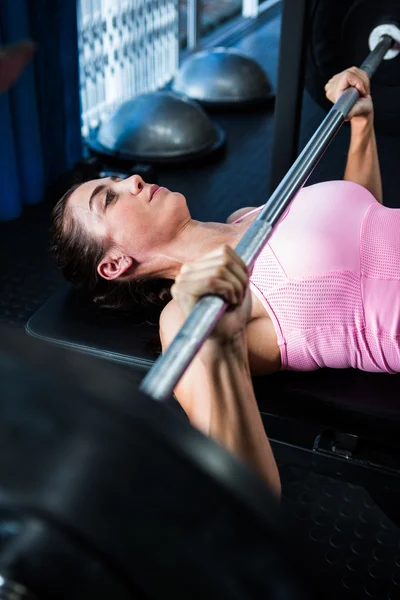 Atleta femenina sosteniendo barra en el gimnasio —  Fotos de Stock