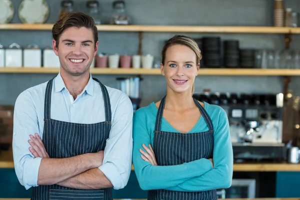 Servitör och servitris som står med armarna korsade — Stockfoto