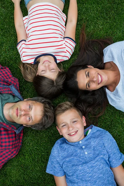 Família feliz deitado na grama no parque — Fotografia de Stock