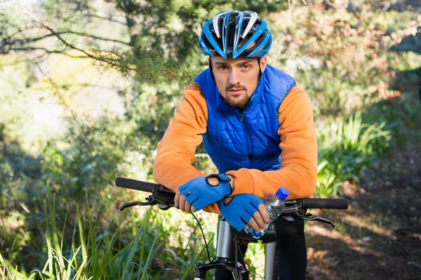 Mannelijke mountainbiker met fiets in bos — Stockfoto
