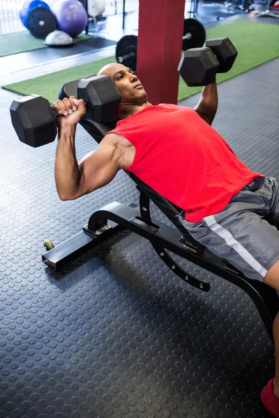 Man exercising with dumbbells on bench — Stock Photo, Image