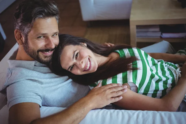 Couple lying on sofa in living room — ストック写真