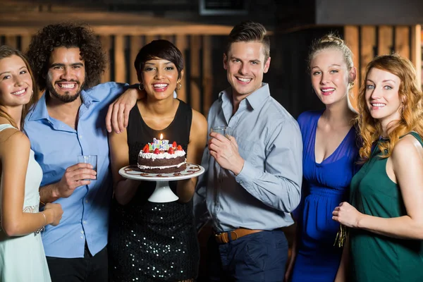 Woman holding birthday cake with friends — Stock Photo, Image