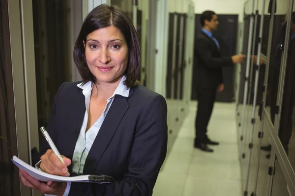 Technician maintaining record of rack mounted server — Stock Photo, Image