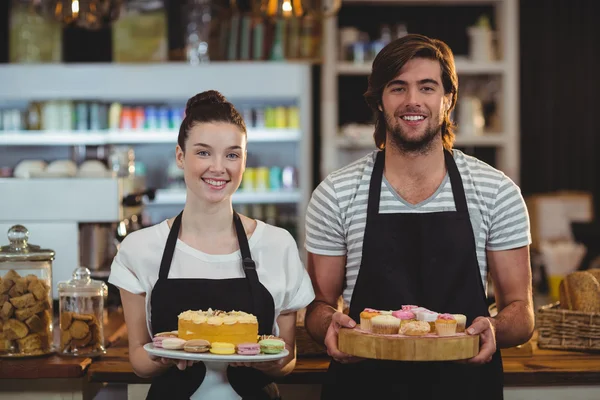 Kellnerin und Kellnerin halten Tablett mit Cupcakes — Stockfoto