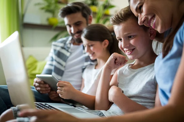 Famille heureuse en utilisant un ordinateur portable et une tablette numérique dans le salon — Photo