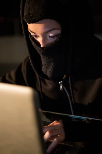 Kvinna i balaclava med laptop — Stockfoto