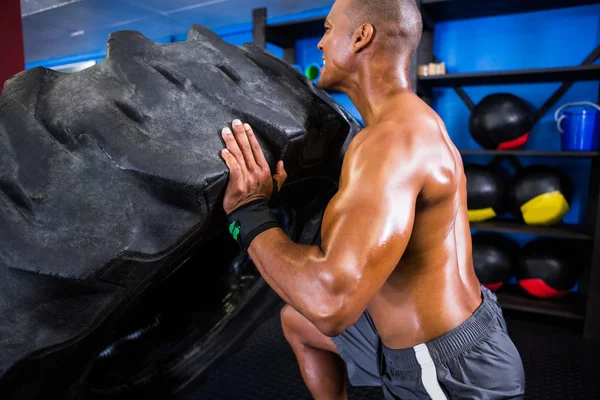 Shirtless athlete pushing tire — Stock Photo, Image