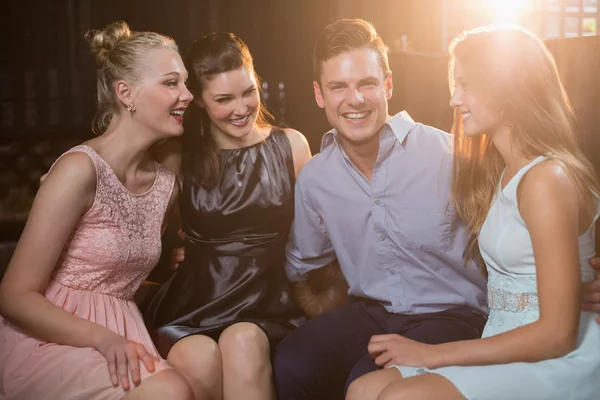 Amis souriants assis ensemble dans le canapé — Photo