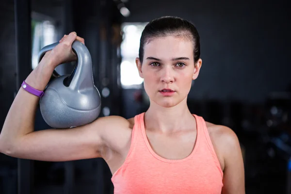 Seriös kvinnliga idrottare håller kettlebell i gymmet — Stockfoto