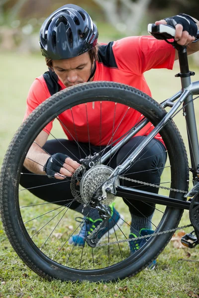 Motociclista de montanha masculino fixar sua cadeia de bicicletas — Fotografia de Stock