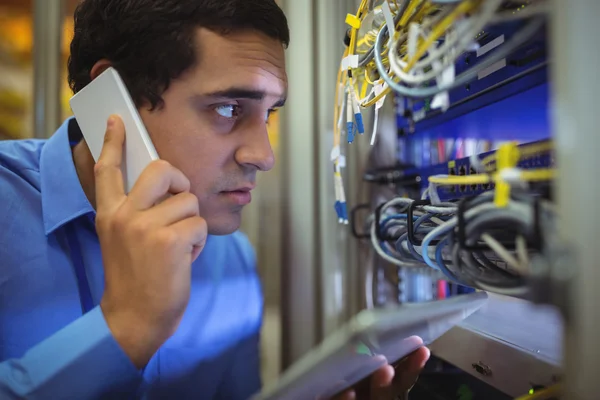 Technician talking on phone while analyzing server — Stock fotografie