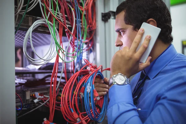 Technicien parlant au téléphone tout en vérifiant les câbles — Photo