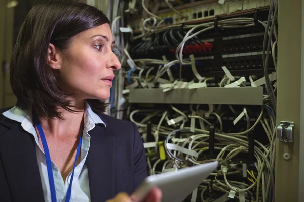 Technician using digital tablet while analyzing server — ストック写真