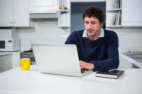 Homem usando laptop na cozinha — Fotografia de Stock