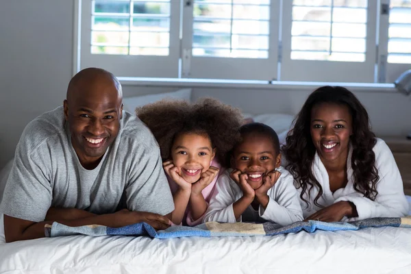 Familia feliz acostada en la cama — Foto de Stock