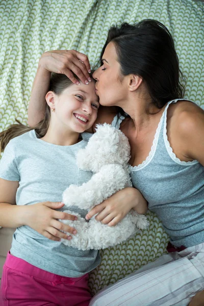 Mãe beijando na testa filha na cama — Fotografia de Stock