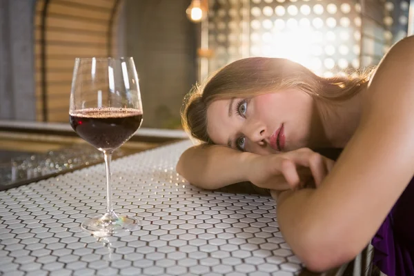 Mulher deitada no balcão de bar com copo de vinho na mesa — Fotografia de Stock