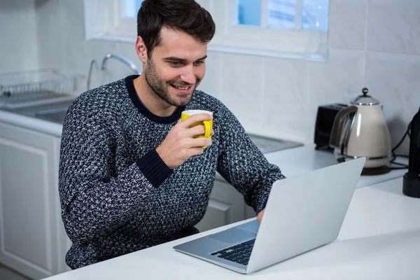 ノート パソコンを使用しながらコーヒーのマグカップを保持している男 — ストック写真